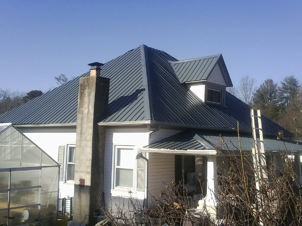 Dark blue standing seam metal roof on a white farmhouse with dormer — Slate & Tile Roof Repair by Roofing Brothers in Fulks Run