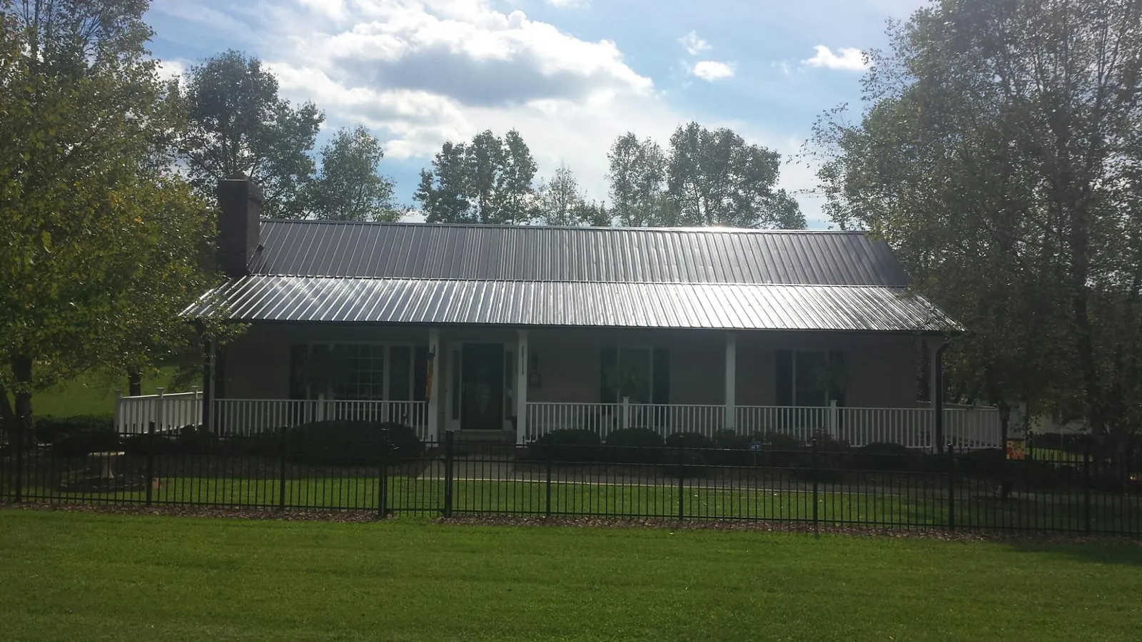 Gray metal roof on a brick ranch with a full width front porch — Gutter Guard Installation work by our crew in Fulks Run