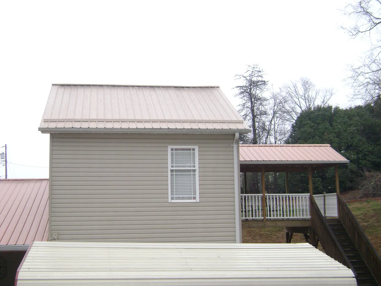 Tan metal roofs on a two story addition and attached porch, from a Roof Replacement job in Fulks Run