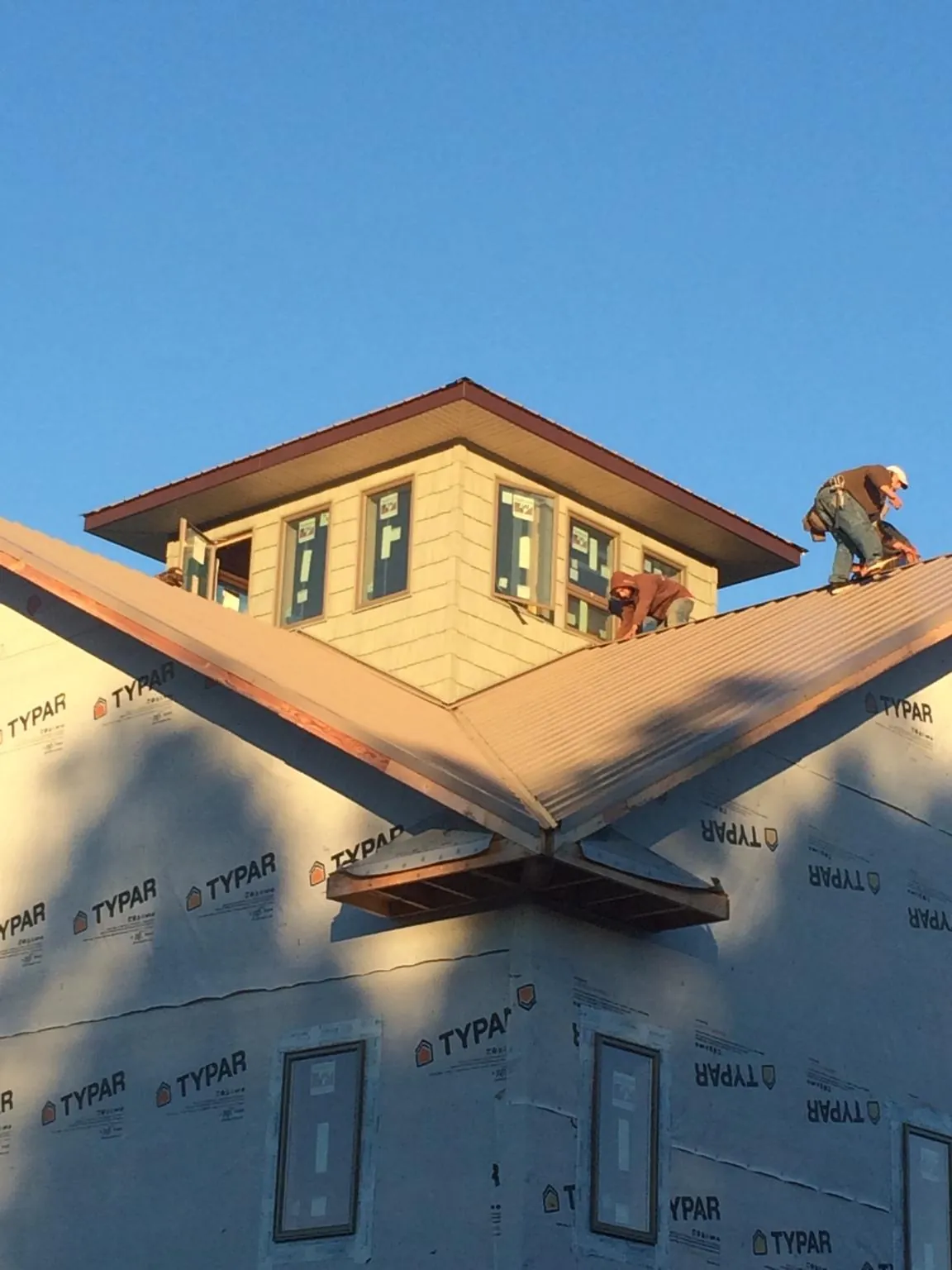 Roofers working around a rooftop cupola on a new metal roof at sunset — Roof Waterproofing in Fulks Run by Roofing Brothers